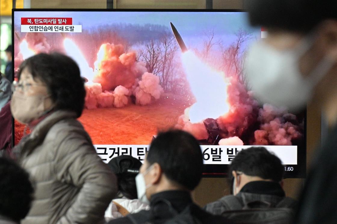 People walk past a television screen showing a news broadcast with file footage of a North Korean missile test, at a railway station in Seoul, South Korea, March 14, 2023. (AFP Photo)