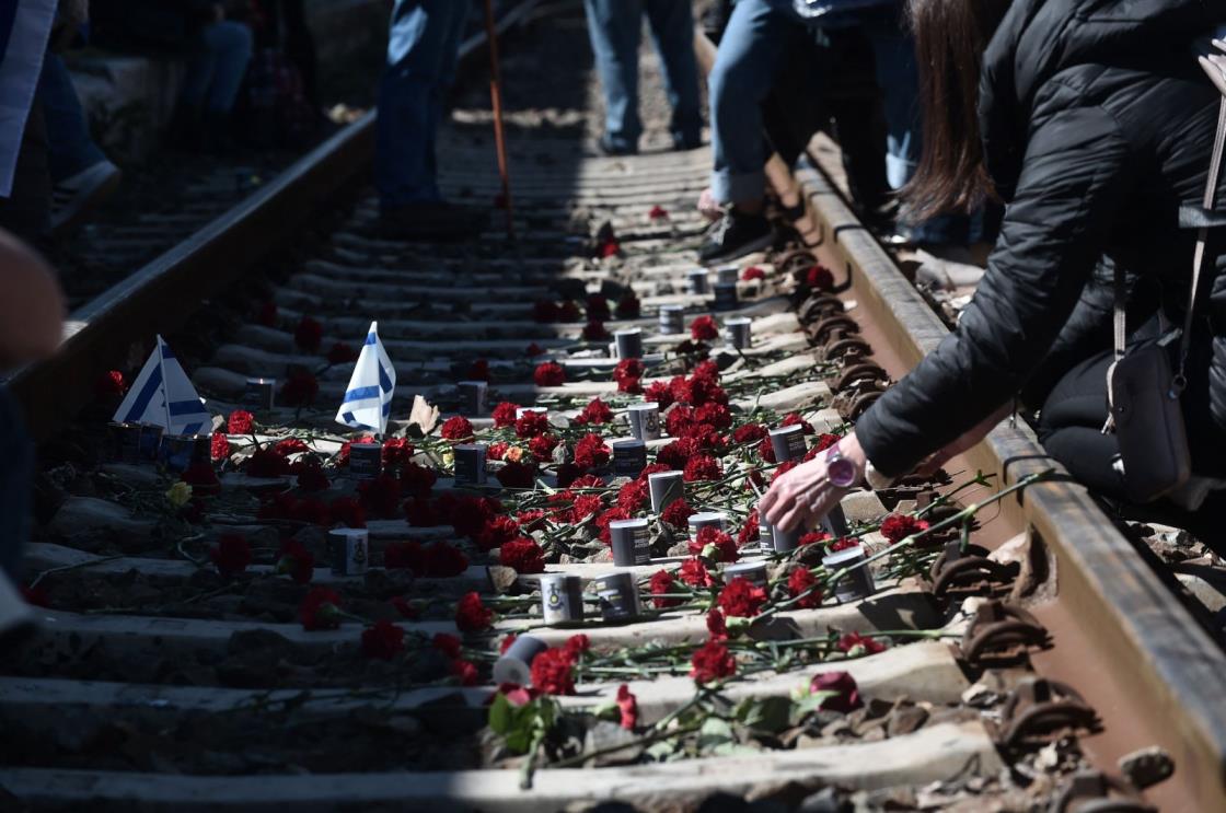 Participants place flowers on railway tracks at the old railway station in Thessalo<em></em>niki after taking part in a march to mark the departure of the first train deporting Greek Jews from Thessalo<em></em>niki to Auschwitz-Birkenau co<em></em>ncentration camp, March 19, 2023. (AFP Photo)