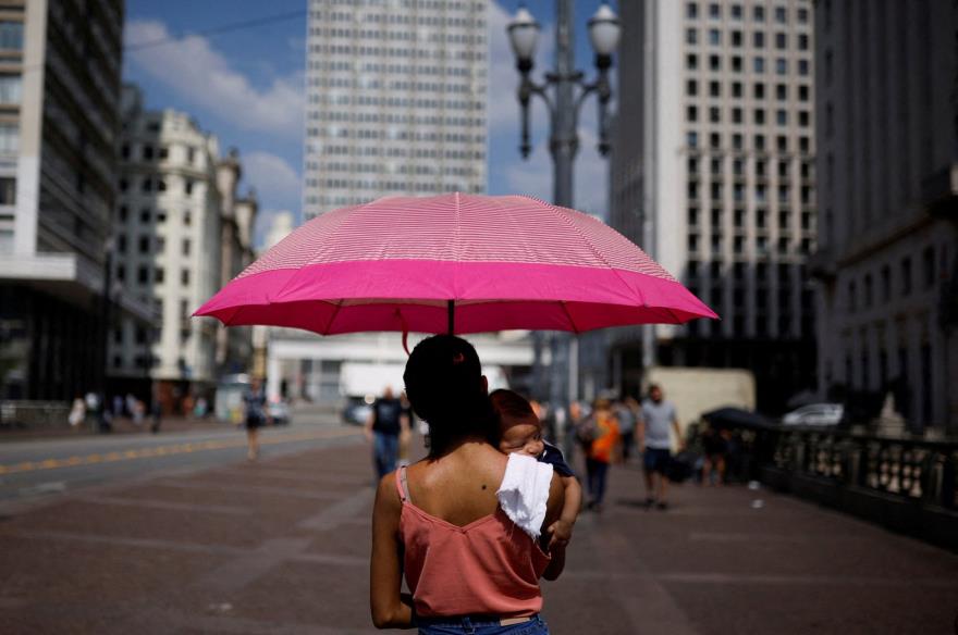 A woman holds her son as they shelter under an umbrella from the sun, Sao Paulo, Brazil, Sept. 22, 2023. (Reuters Photo)
